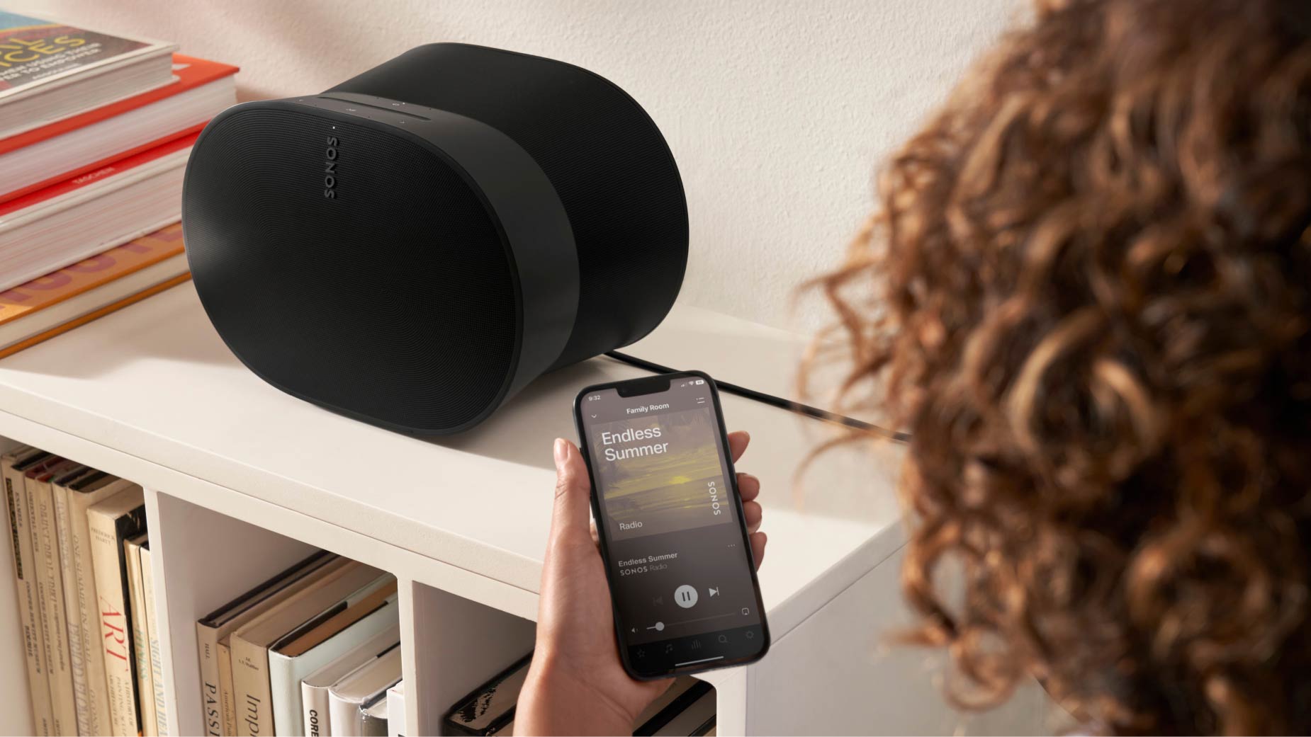 Frau mit Smartphone bedient Sonos Era 300 via Sonos App