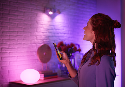 Philips Hue Lampen und Frau mit Smartphone-App